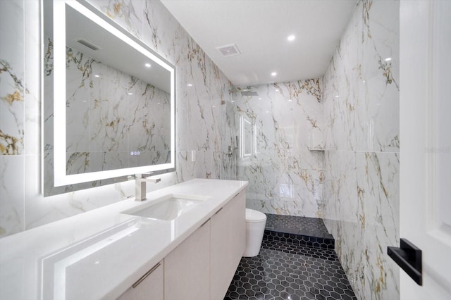 bathroom featuring tile floors, oversized vanity, toilet, and tile walls