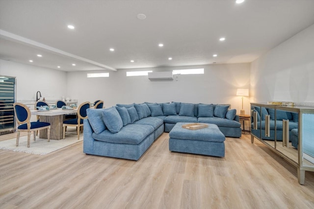 living room with a wall unit AC and light hardwood / wood-style flooring