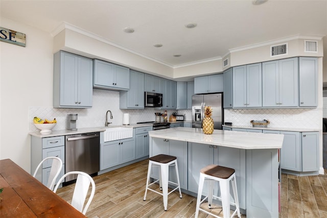 kitchen featuring a center island, a breakfast bar, appliances with stainless steel finishes, backsplash, and sink