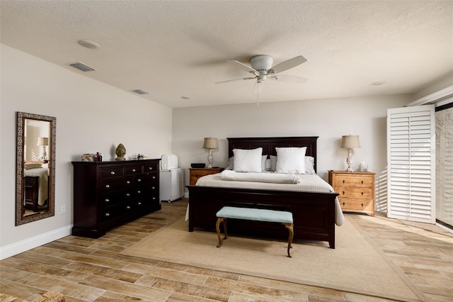 bedroom with light hardwood / wood-style floors, ceiling fan, and a textured ceiling