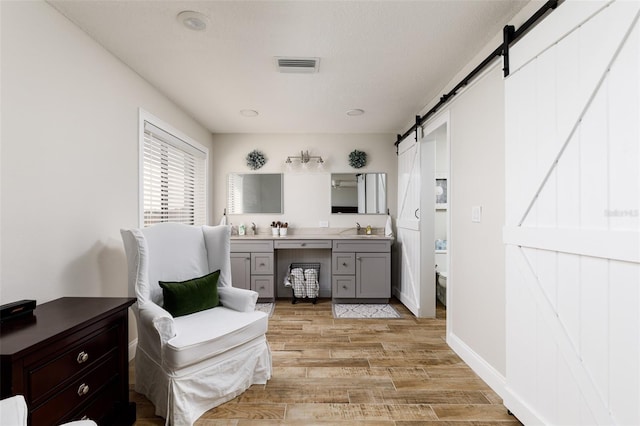 interior space with a barn door, sink, and light wood-type flooring