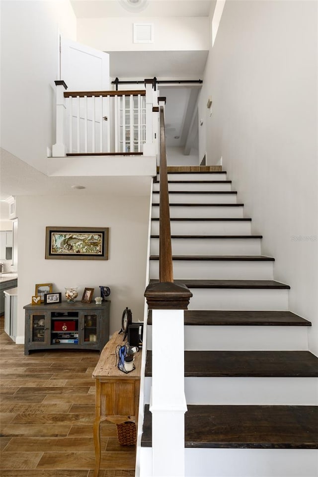 staircase with a high ceiling, dark hardwood / wood-style floors, and a barn door