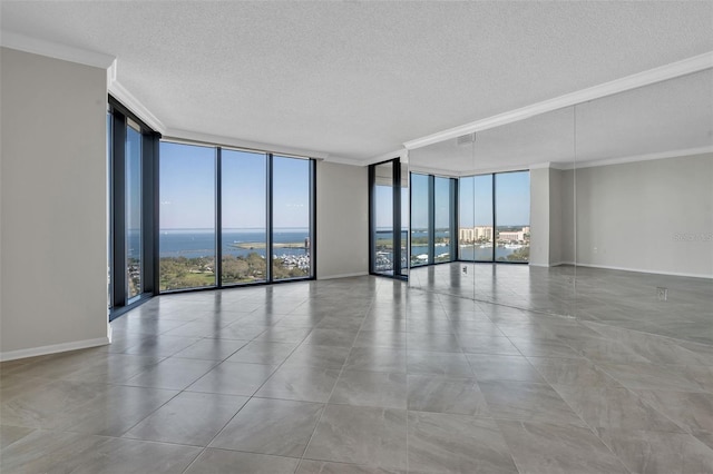 spare room featuring light tile floors, ornamental molding, a water view, and a wall of windows