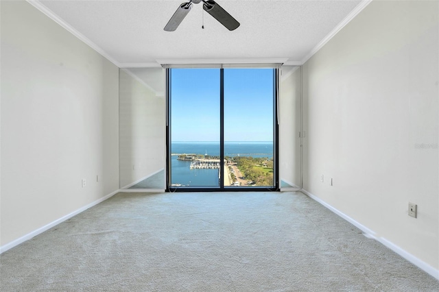 empty room with ceiling fan, floor to ceiling windows, crown molding, light carpet, and a water view