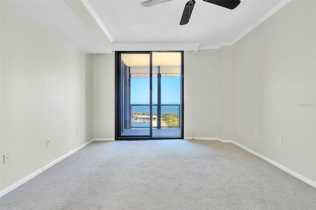 carpeted empty room featuring a textured ceiling, crown molding, ceiling fan, and a water view