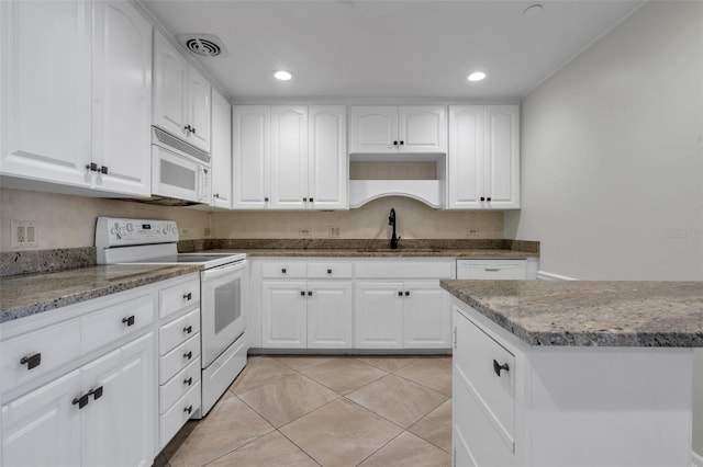 kitchen with white appliances, sink, light tile floors, dark stone countertops, and white cabinetry