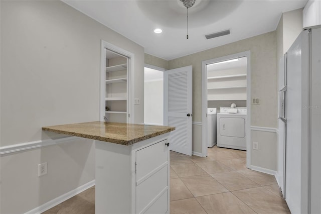 kitchen featuring ceiling fan, white refrigerator with ice dispenser, stone counters, separate washer and dryer, and white cabinetry