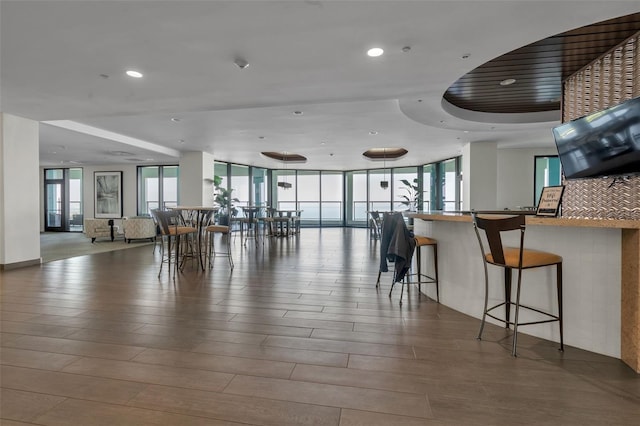 interior space with a raised ceiling, a breakfast bar area, and floor to ceiling windows