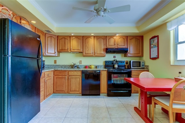 kitchen featuring crown molding, light tile patterned floors, a raised ceiling, light stone countertops, and black appliances