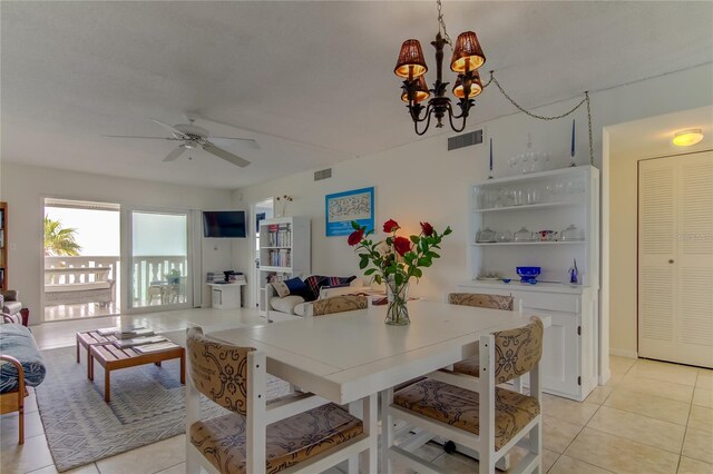 tiled dining room with ceiling fan with notable chandelier