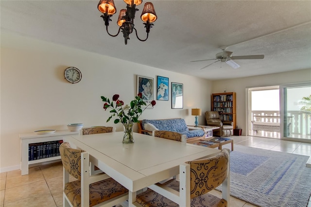 tiled dining space featuring ceiling fan with notable chandelier and a textured ceiling