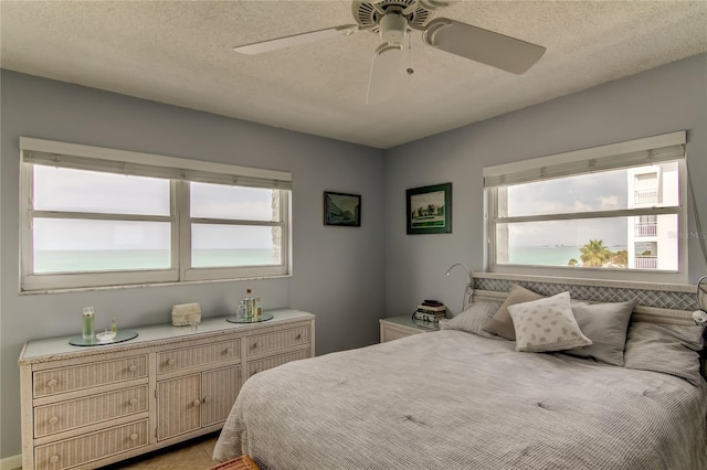 bedroom featuring multiple windows, ceiling fan, and a textured ceiling