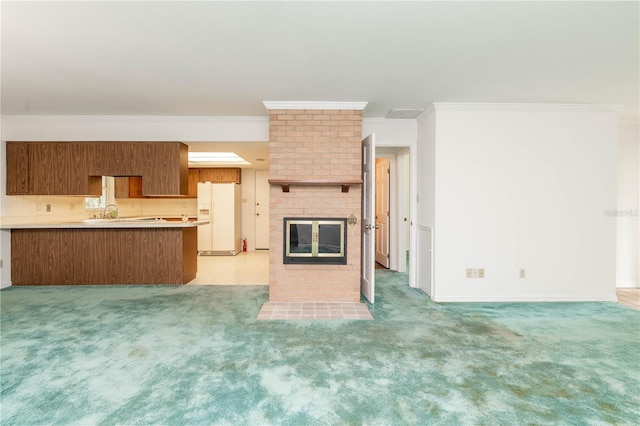 unfurnished living room featuring brick wall, a brick fireplace, sink, ornamental molding, and light carpet