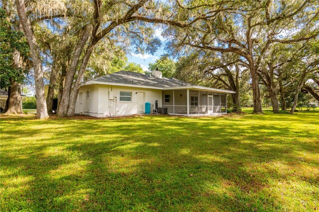 rear view of property with a lawn and a sunroom