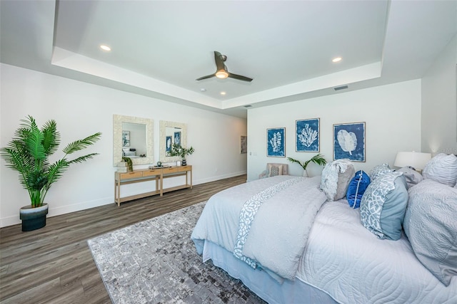 bedroom with dark wood-type flooring, ceiling fan, and a raised ceiling