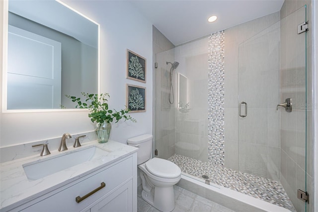 bathroom with a shower with door, tile flooring, vanity, and toilet