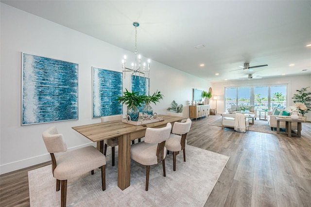 dining room with ceiling fan with notable chandelier and light hardwood / wood-style flooring