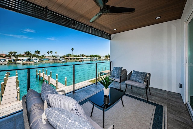 balcony with outdoor lounge area, ceiling fan, and a water view