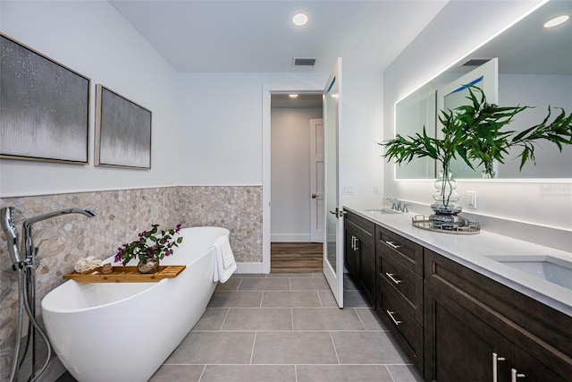 bathroom with a bath to relax in, tile floors, and dual bowl vanity