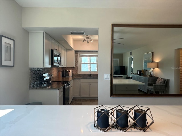 kitchen featuring sink, tasteful backsplash, appliances with stainless steel finishes, dark stone counters, and white cabinets