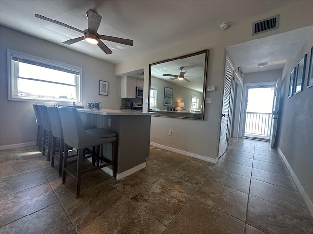 kitchen with white cabinetry, ceiling fan, a breakfast bar, and kitchen peninsula