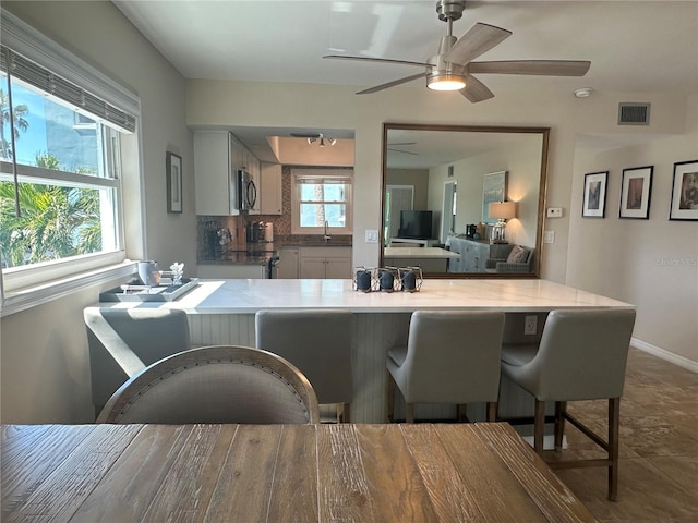 kitchen featuring a kitchen breakfast bar, kitchen peninsula, sink, and decorative backsplash