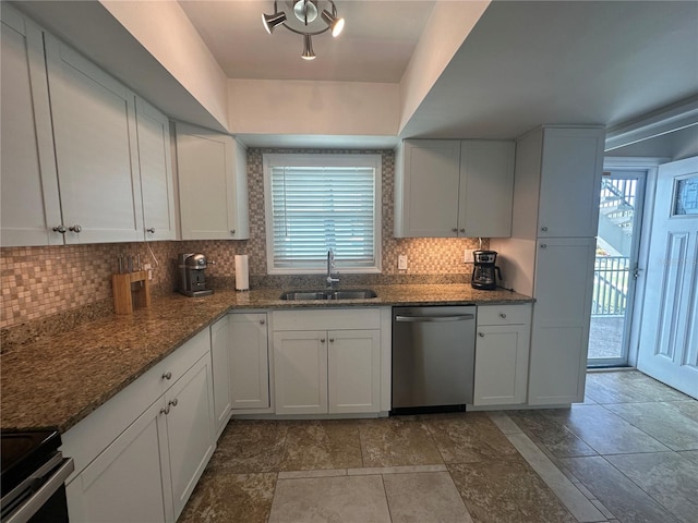 kitchen with white cabinetry, stainless steel appliances, sink, and dark stone countertops