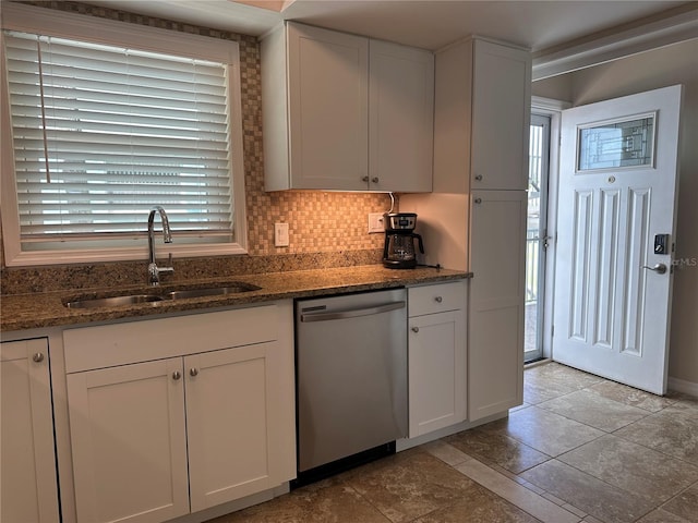 kitchen featuring stainless steel dishwasher, dark stone counters, sink, and white cabinets