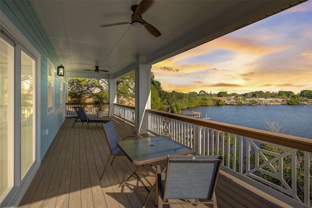 deck at dusk featuring ceiling fan and a water view