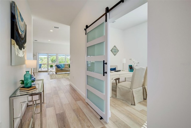 hallway with light hardwood / wood-style floors and a barn door