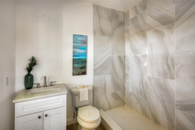 bathroom with vanity, toilet, and a tile shower