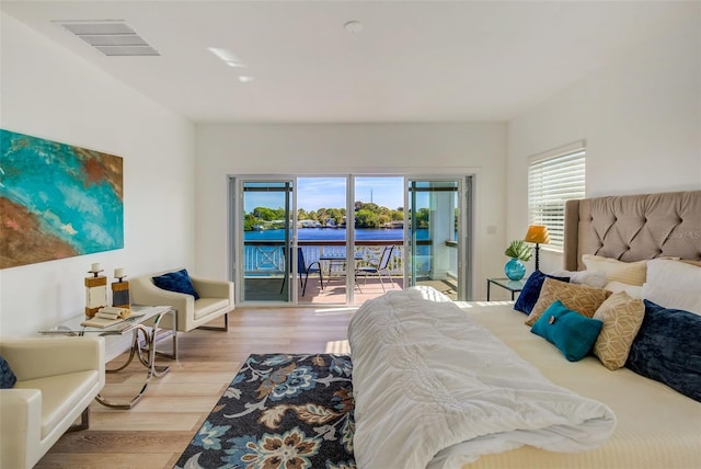 bedroom with a water view, light wood-type flooring, and access to outside