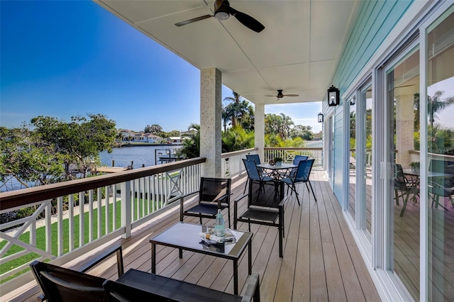 wooden deck with a lawn, ceiling fan, and a water view