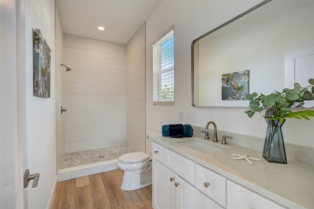 bathroom with vanity, a tile shower, hardwood / wood-style floors, and toilet