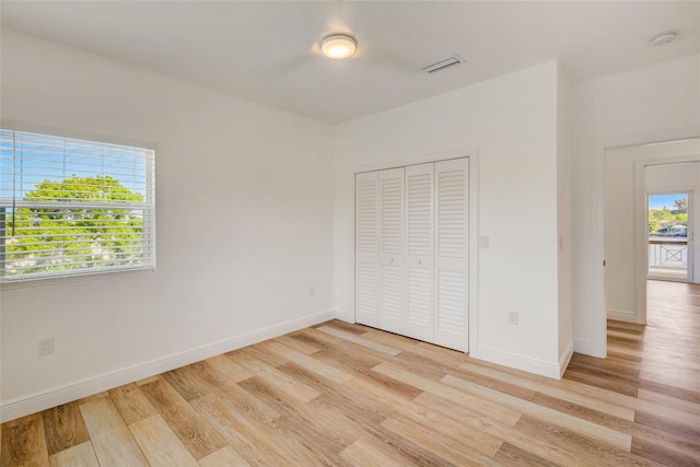 unfurnished bedroom with light hardwood / wood-style flooring and a closet