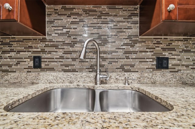 kitchen featuring sink, tasteful backsplash, and light stone counters