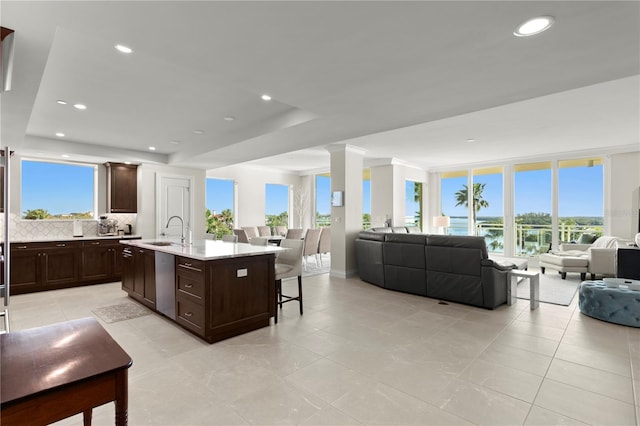 interior space with light tile flooring, a healthy amount of sunlight, tasteful backsplash, and dark brown cabinets