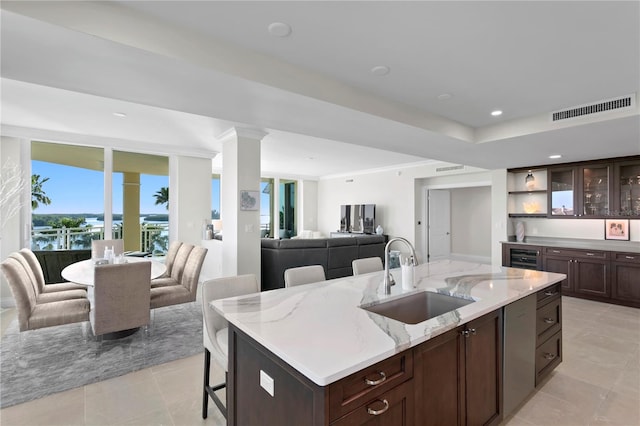 kitchen with a kitchen breakfast bar, an island with sink, sink, and light tile floors