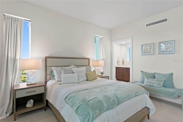 bedroom featuring light carpet and ensuite bath