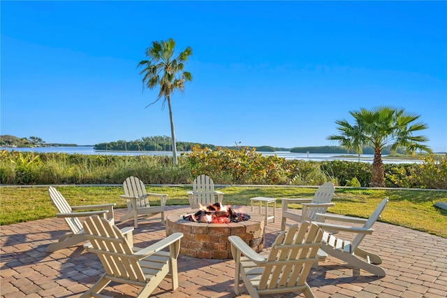 view of terrace with an outdoor fire pit and a water view