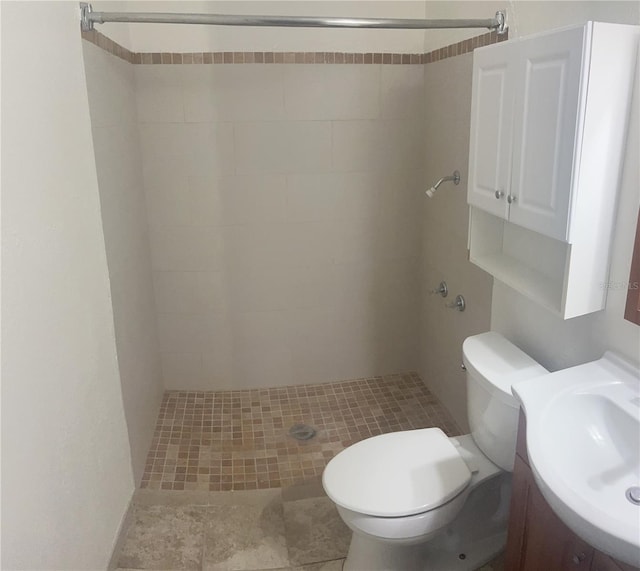 bathroom featuring vanity, tile flooring, a tile shower, and toilet