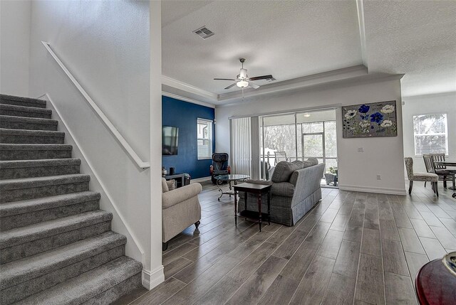 living room featuring a textured ceiling, ceiling fan, crown molding, and dark wood-type flooring