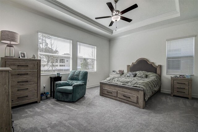 bedroom with ceiling fan, dark carpet, a raised ceiling, and multiple windows