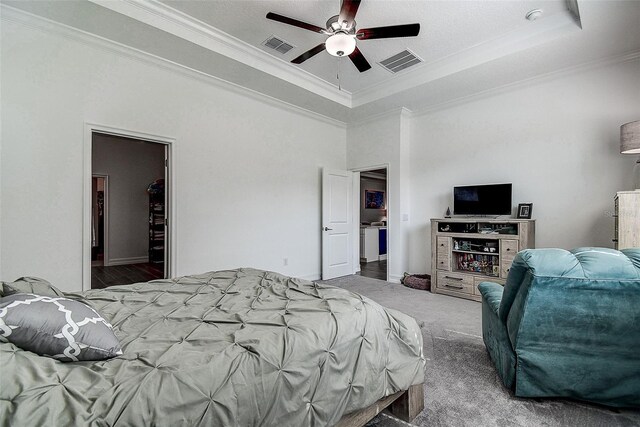 bedroom featuring dark colored carpet, crown molding, ceiling fan, and a tray ceiling