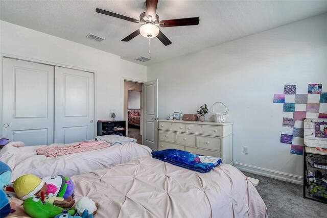 carpeted bedroom featuring ceiling fan, a closet, and a textured ceiling