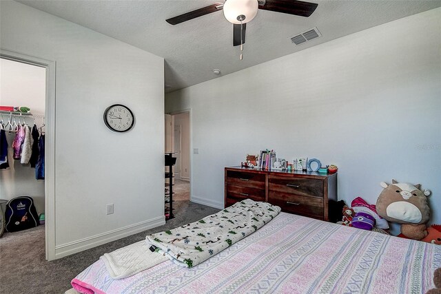 carpeted bedroom with a closet, a spacious closet, ceiling fan, and a textured ceiling