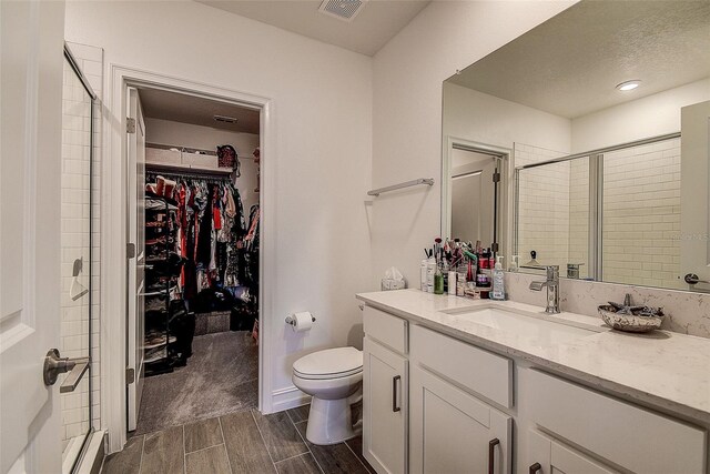 bathroom with a shower with door, toilet, and vanity