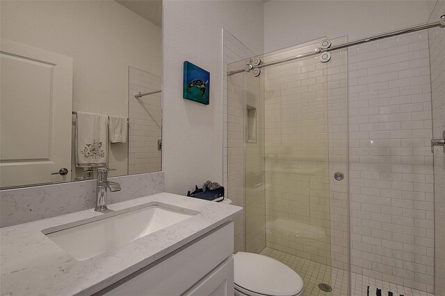 bathroom with a shower with door, toilet, and large vanity