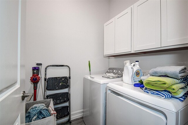 clothes washing area featuring washer and dryer and cabinets