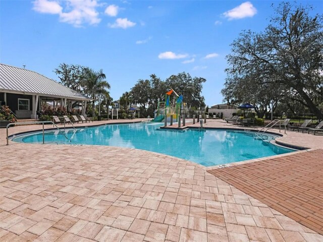 view of pool featuring a playground and a patio area